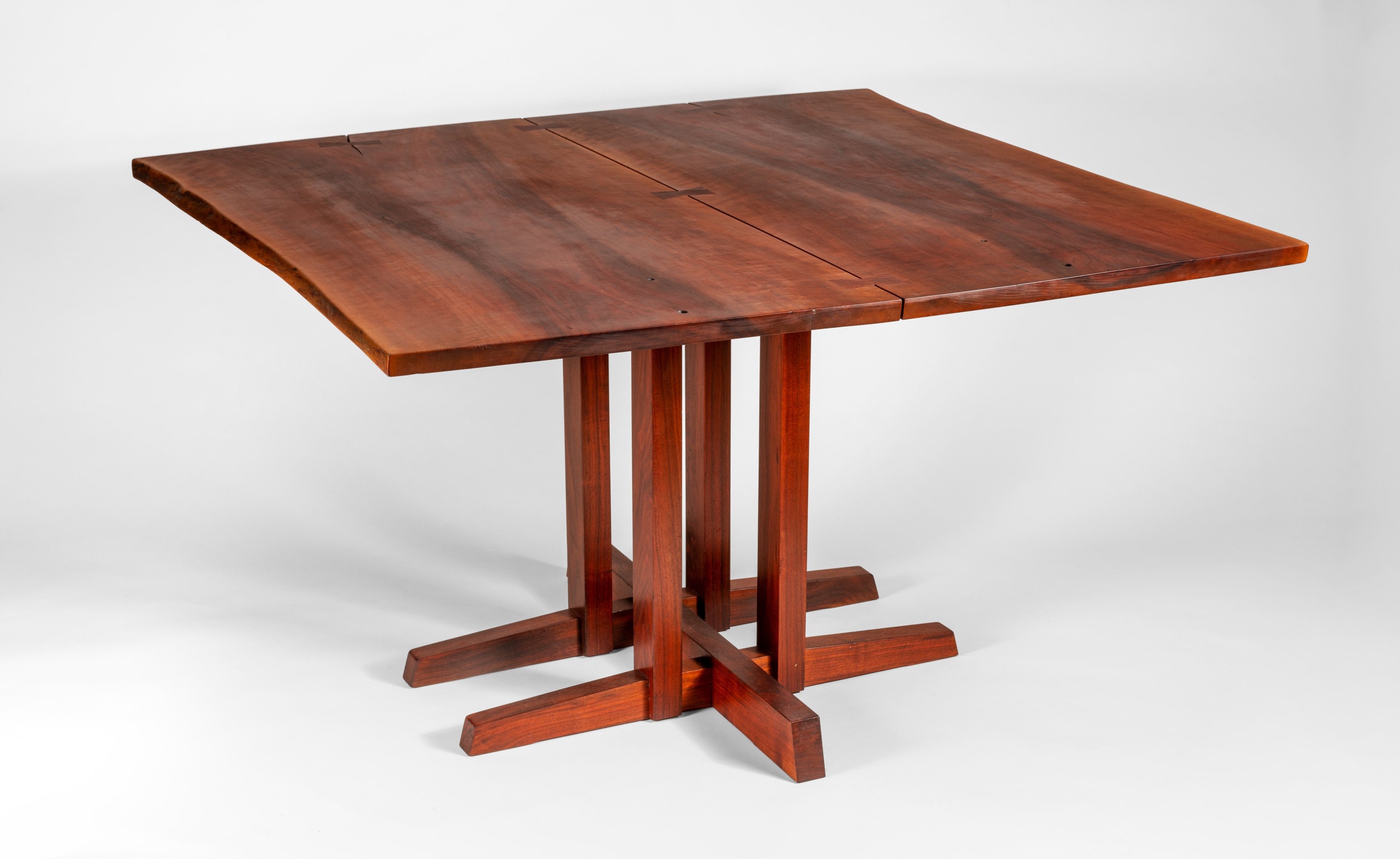 a dining table by george nakashima with squared top formed by several slabs with live-edges connected/strengthened to one another with nakashima butterfly joints