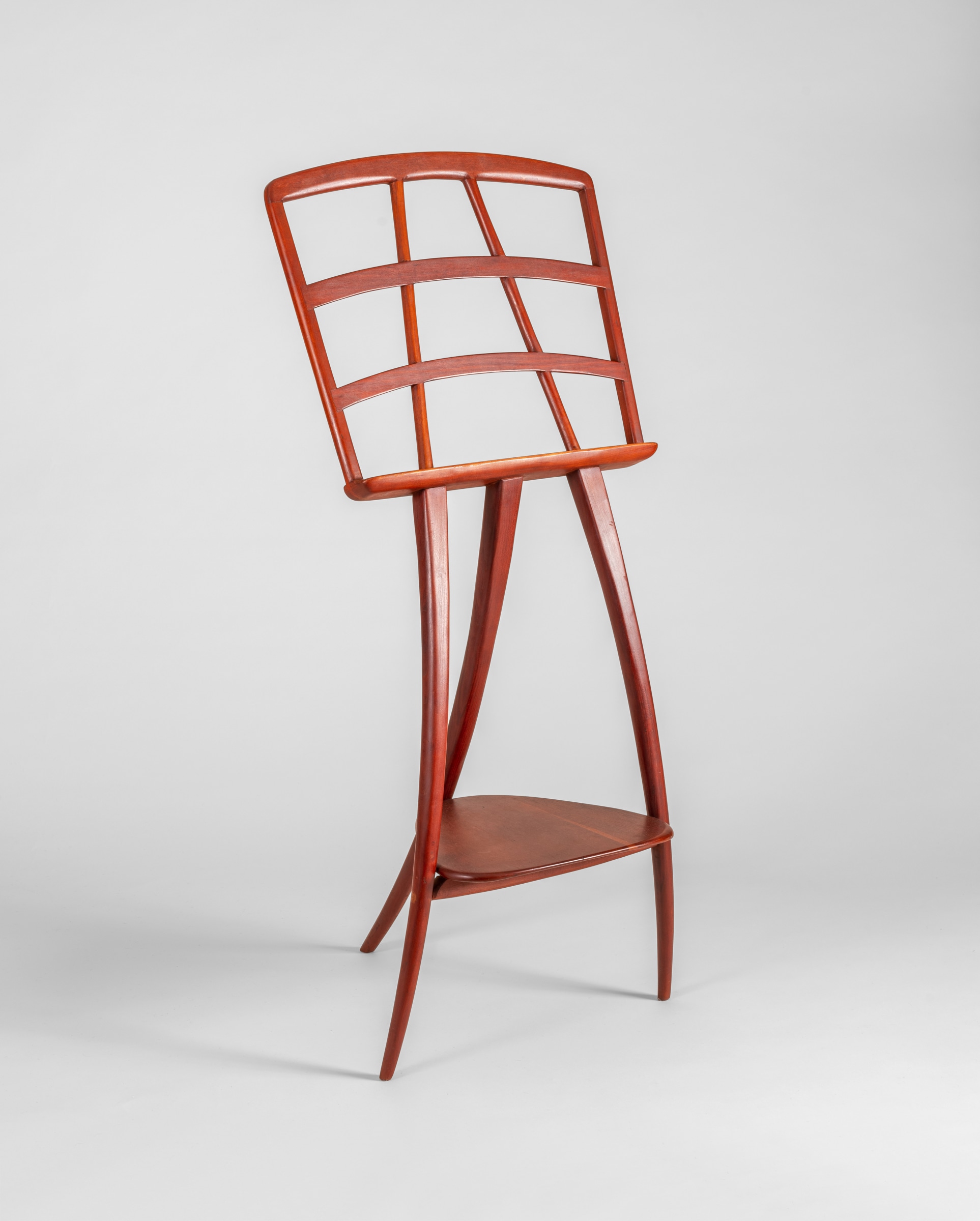 a music stand in the mid-century modern style by american studio craft designer wharton esherick, hand carved wood with soft smooth edges, tripod base