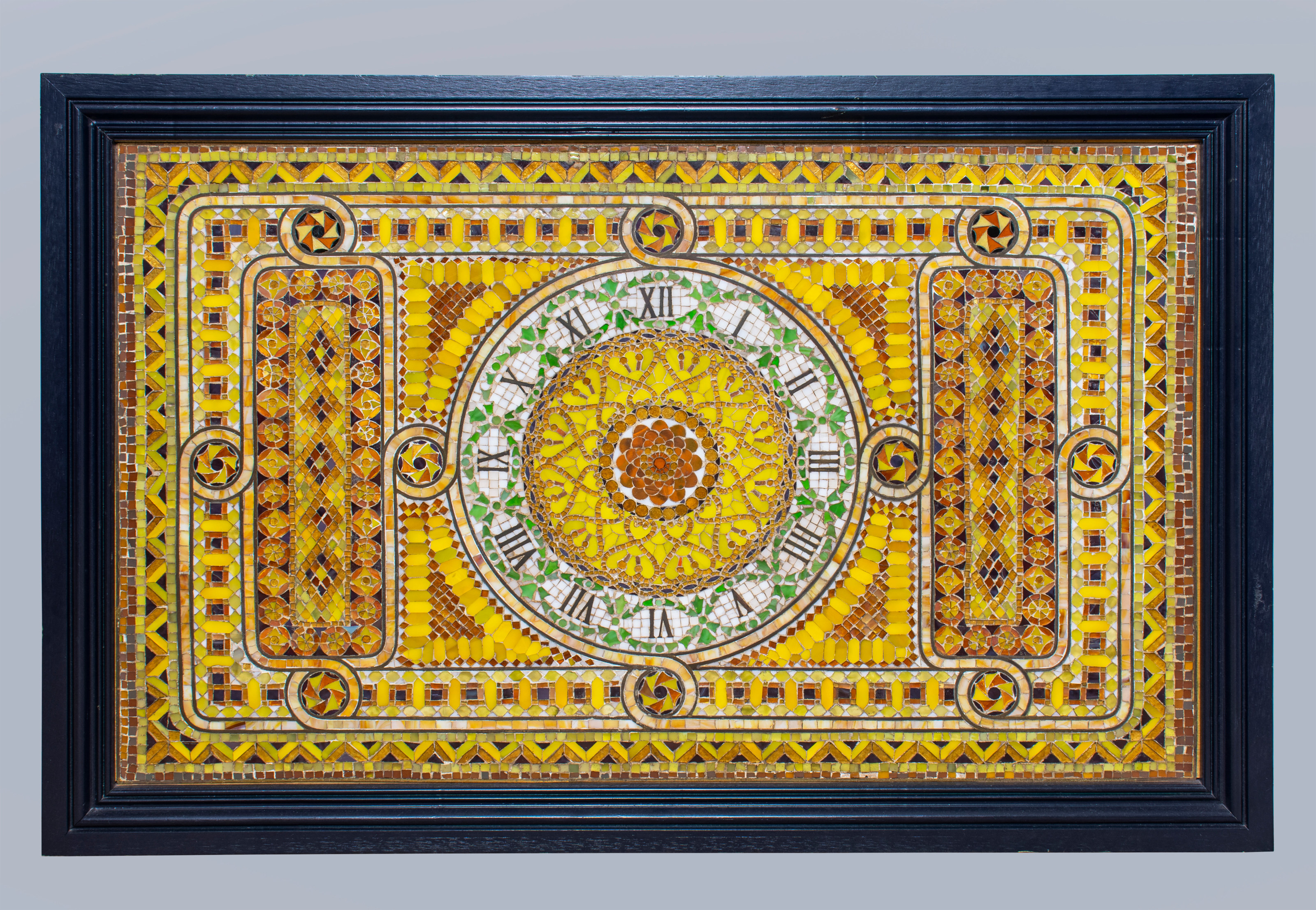 a flat rectangular tiffany favrile glass mosaic panel depicting a clock face in white glass with roman numerals - the background a very bright almost neon yellow glass, decorated in a classical style with geometric scrolls and intricate patterns - there are no clock hands.