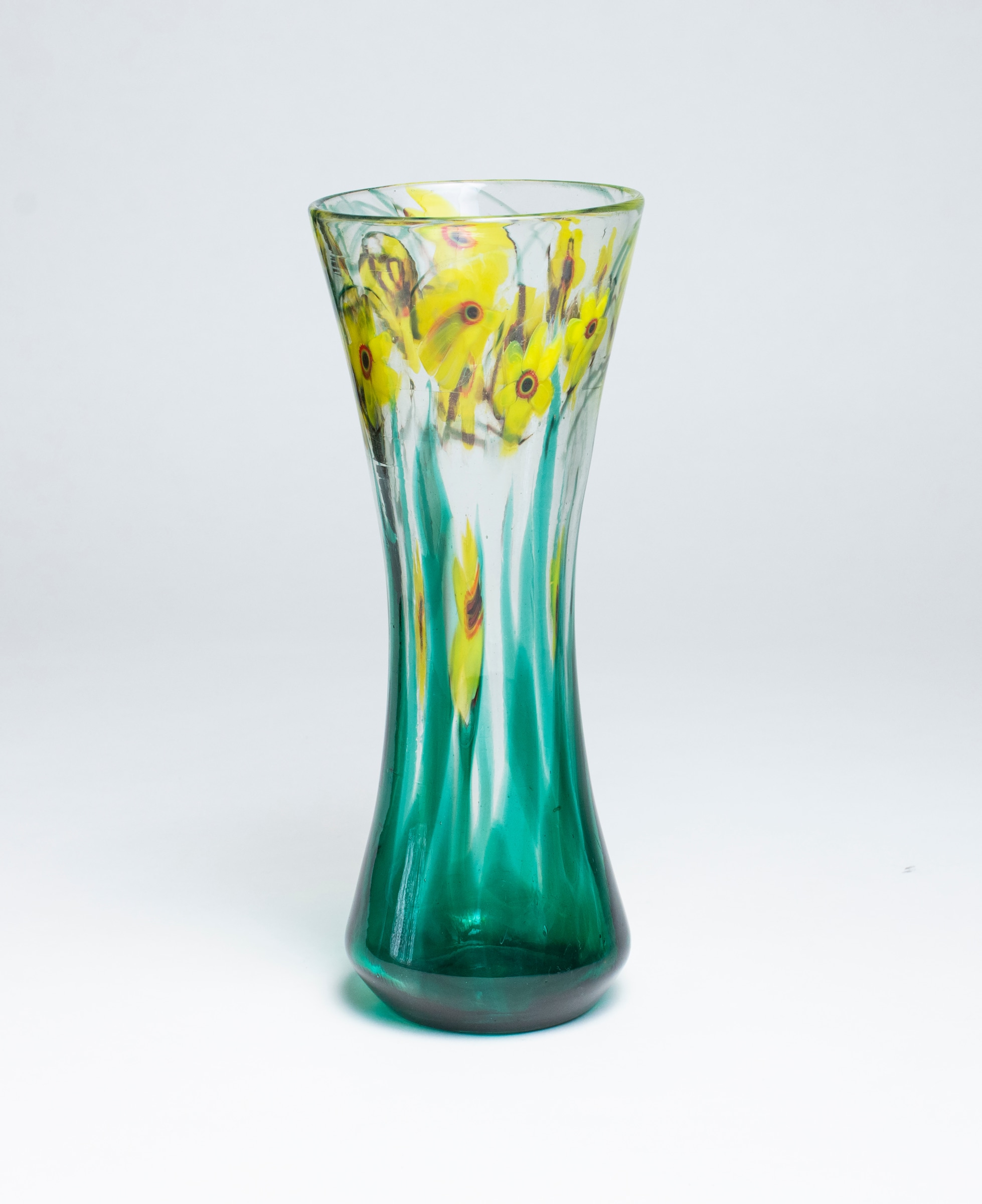 A tiffany favrile glass paperweight vase, cylindrical form with slightly cinched waist and flared rim, the clear glass with motif of bright yellow flowers with five petals and red centers, rising from transparent green stems.