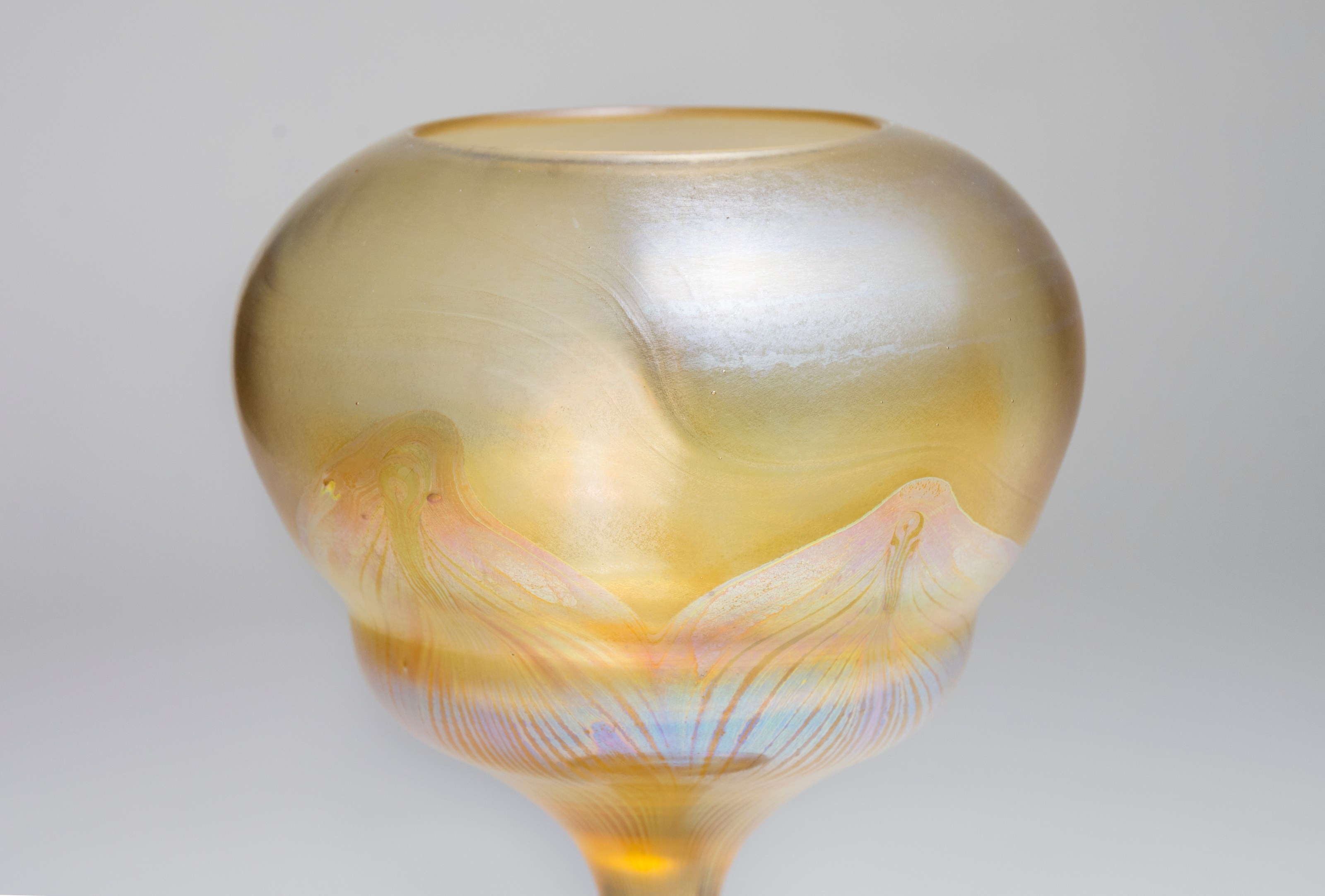 the flower cup of the tiffany favrile glass flower form showing the surface sheen of the transparent yellow glass and the contrast of the iridescent swag decoration