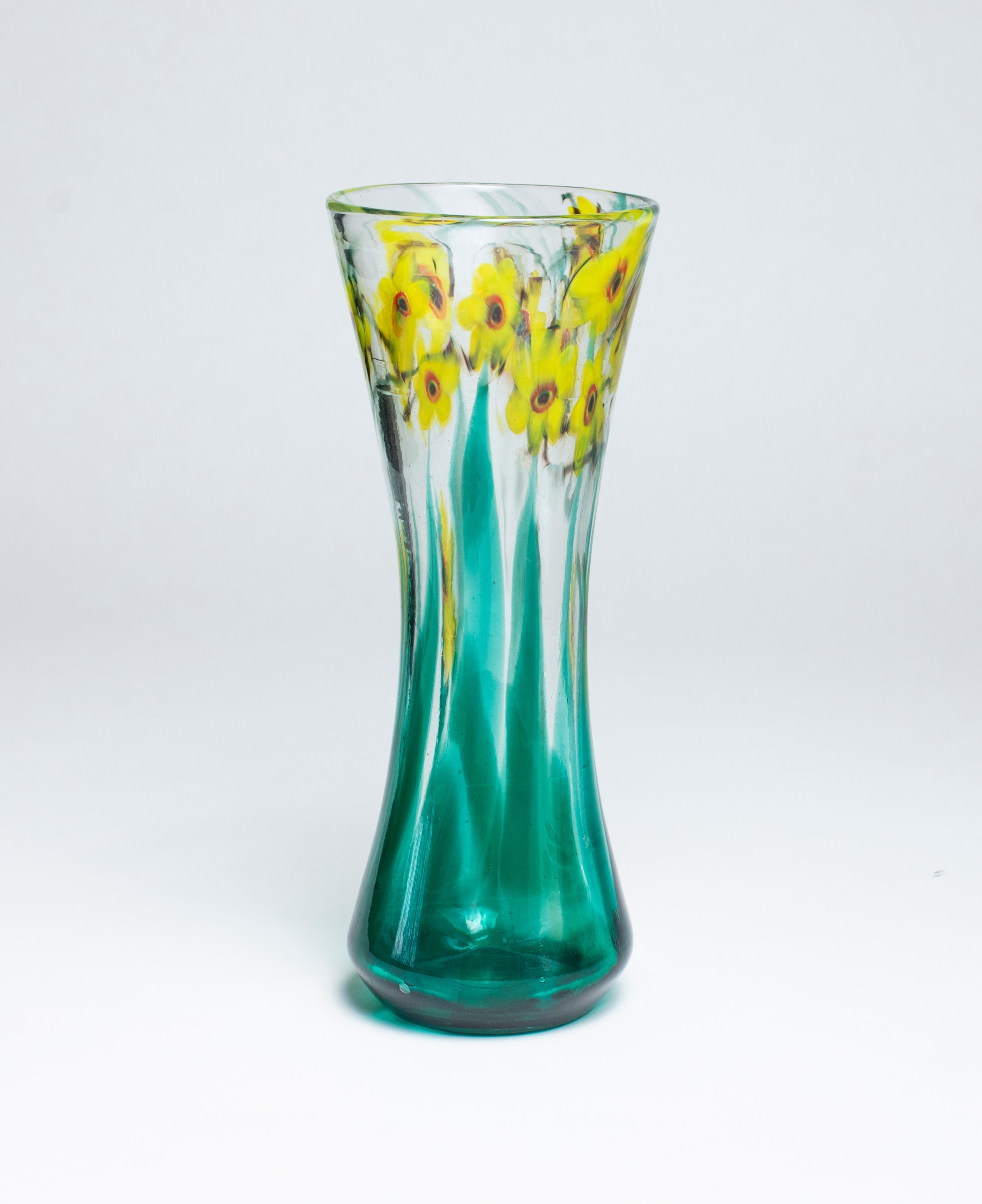 A tiffany favrile glass paperweight vase, cylindrical form with slightly cinched waist and flared rim, the clear glass with motif of bright yellow flowers with five petals and red centers, rising from transparent green stems.