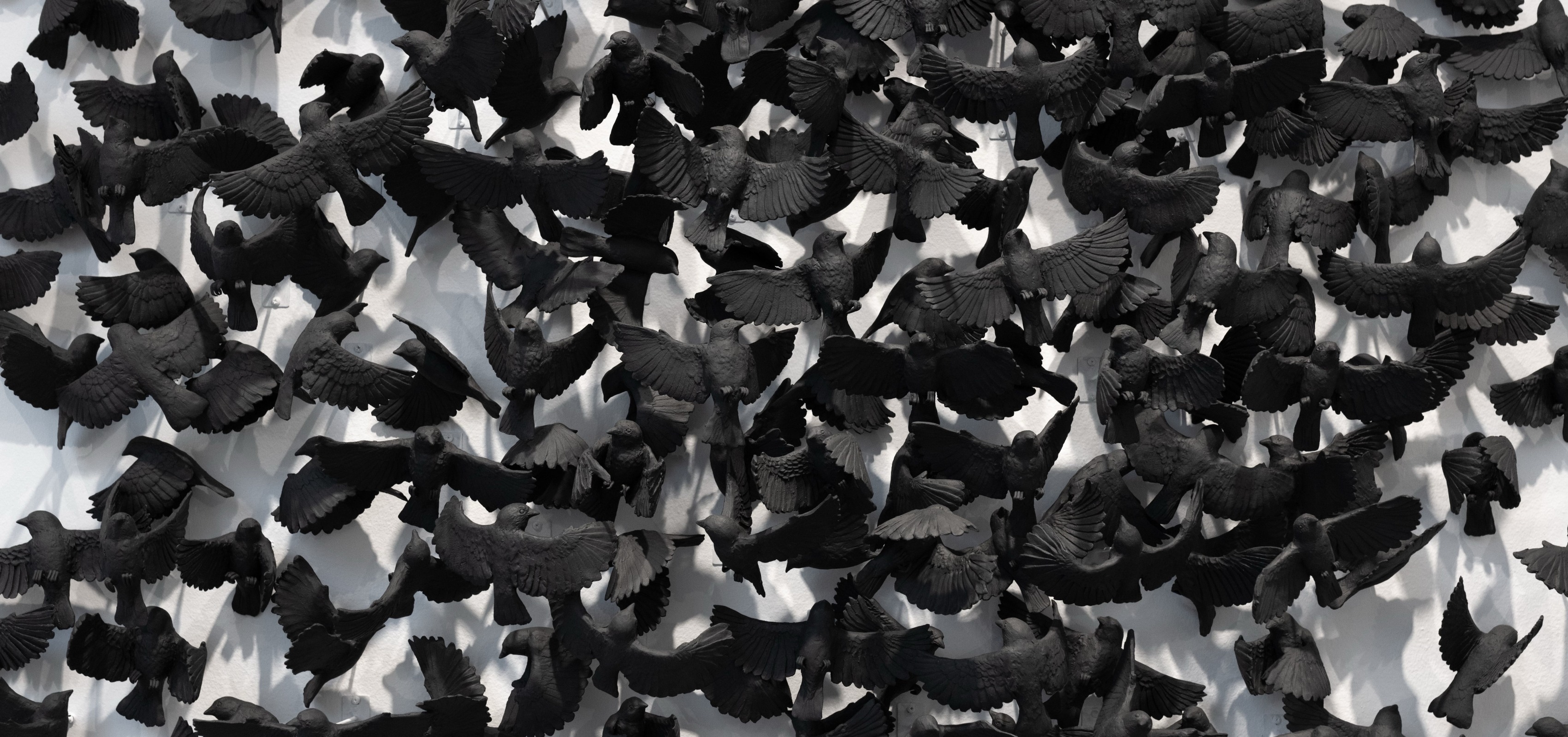 Detail of a ceramic installation of ceramic black sparrows by Camilla Taylor.