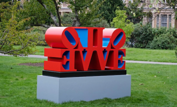 A 54 3/8 by 98 by 32 inch (including the base) polychrome aluminum sculpture consisting of two quadripartite LOVE sculptures side by side, with the L and V of each sculpture back to back and the O and E facing outwards. The faces and sides of the sculpture are red, and the insides are blue.