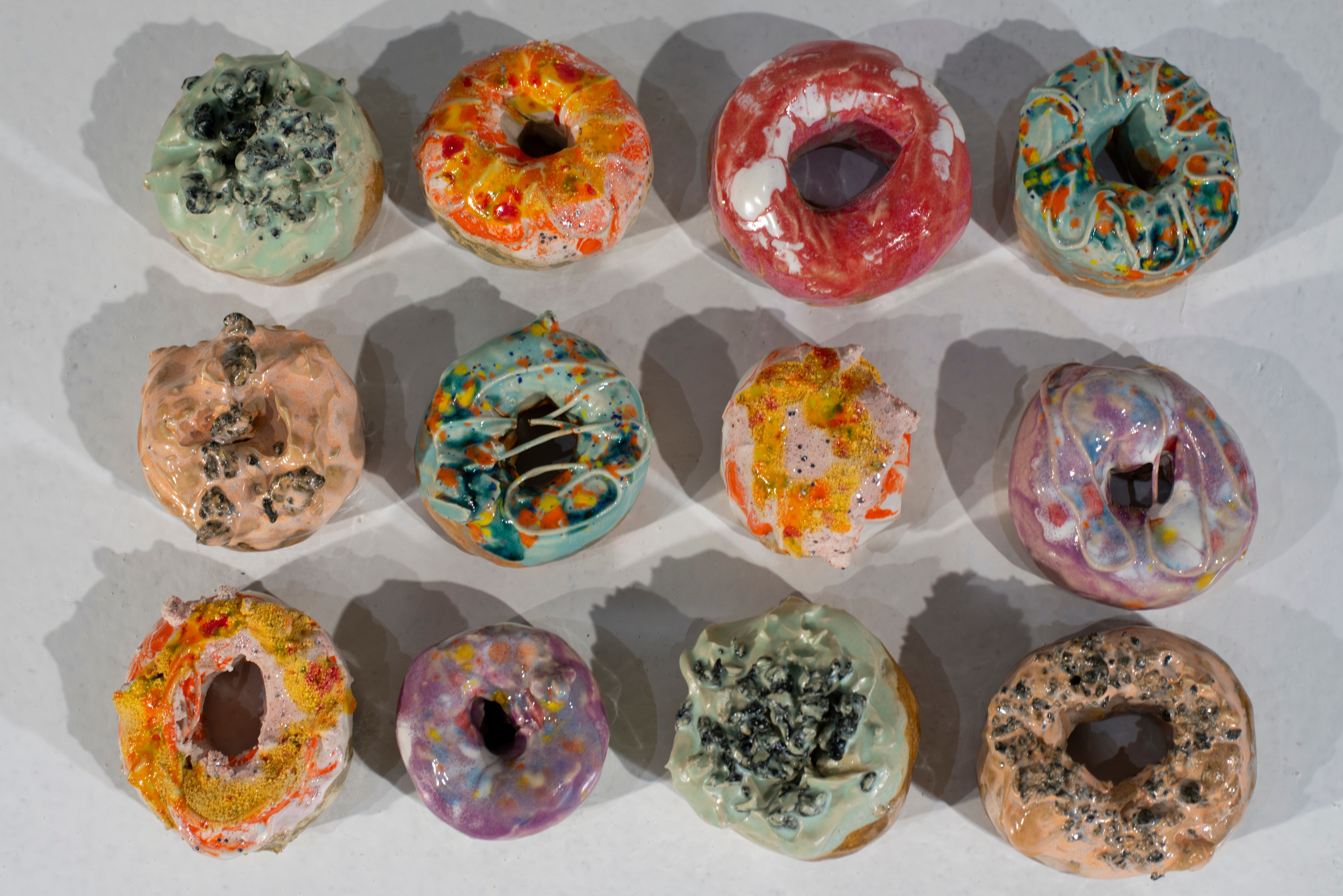 Small ceramic doughnuts, each glazed with a colorful icing.