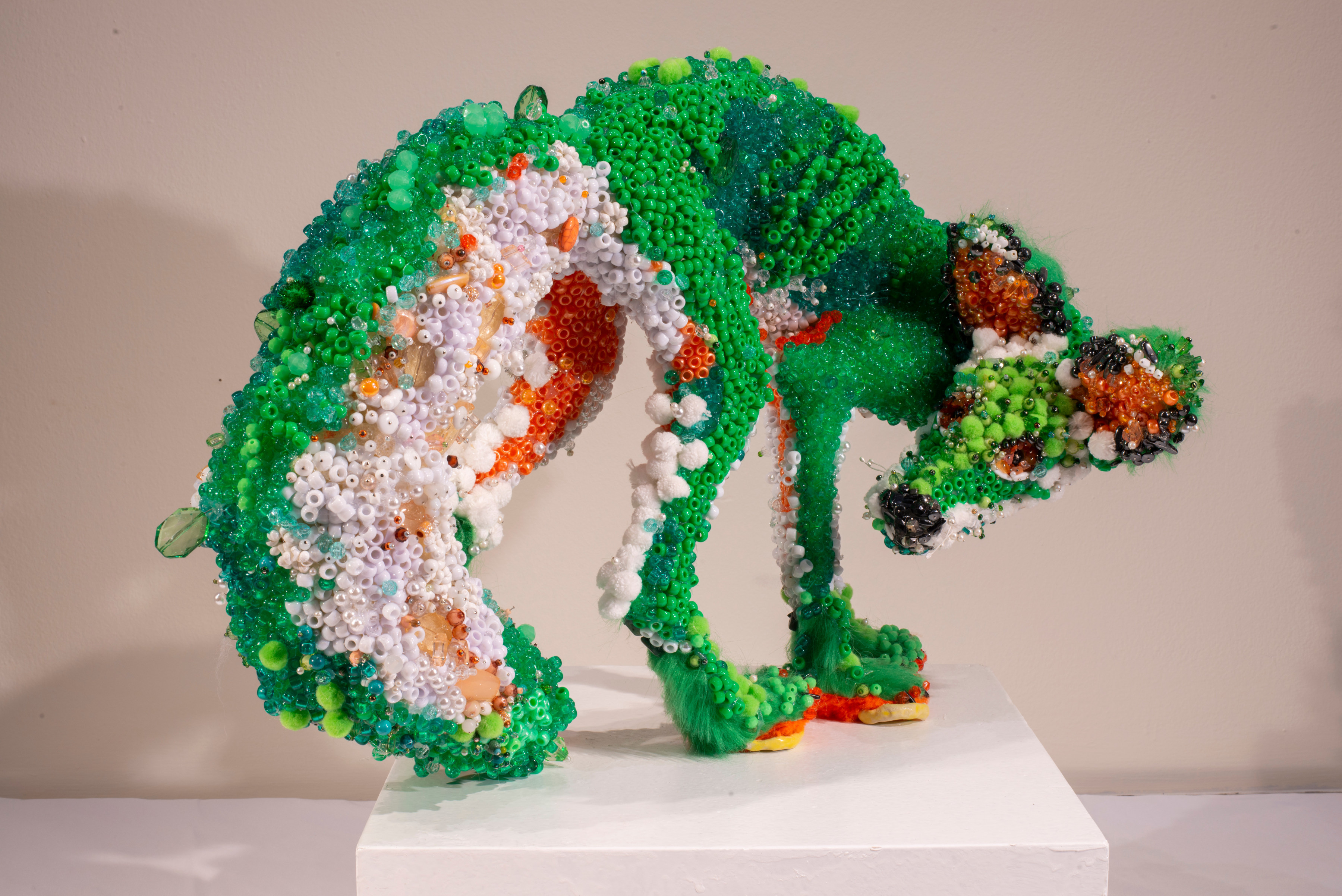 Fox sculpture covered with green, white, and orange beads and glass, glancing over its shoulder.
