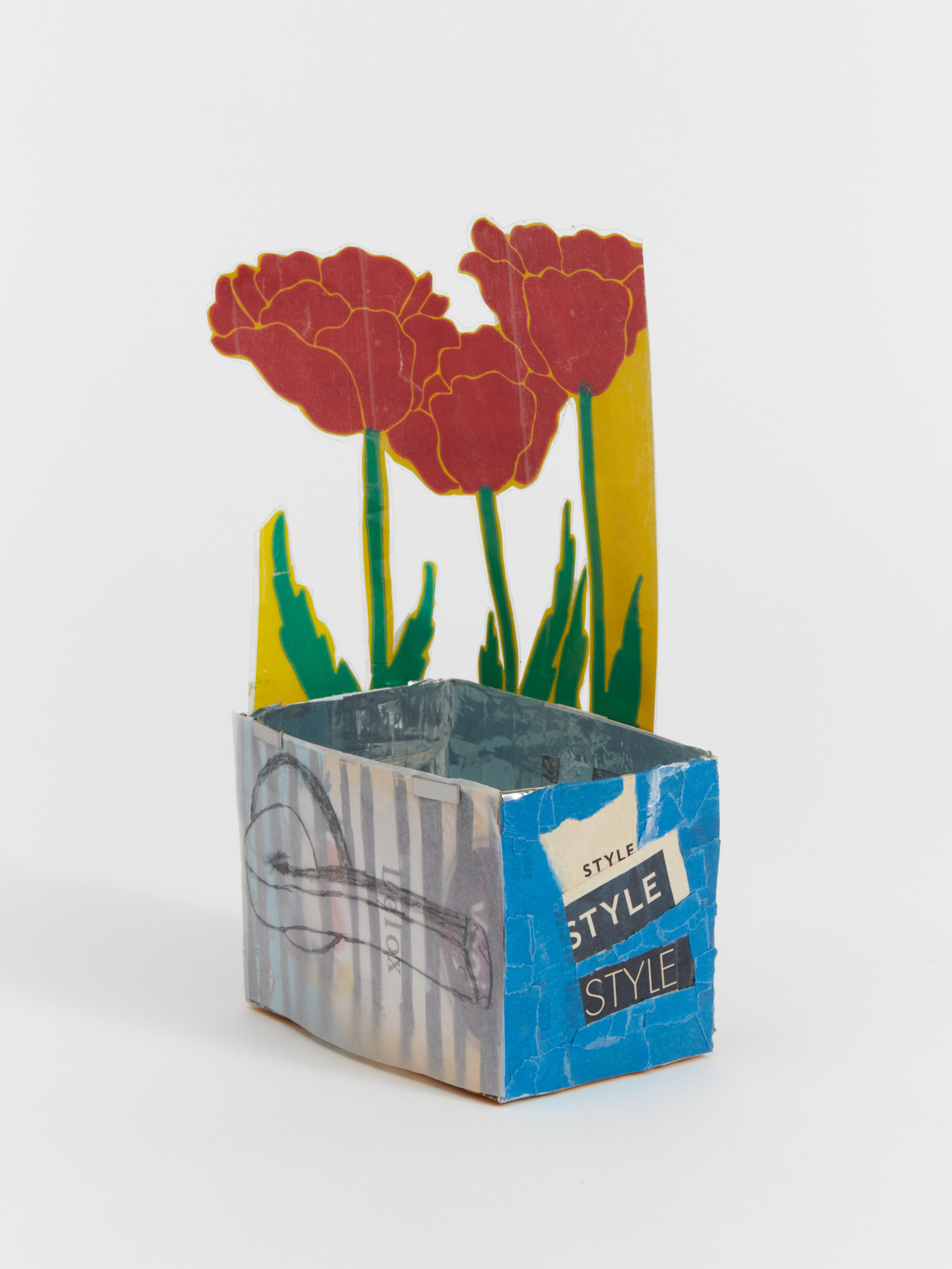 A box like sculpture with cut out red flowers adhered to the side. 