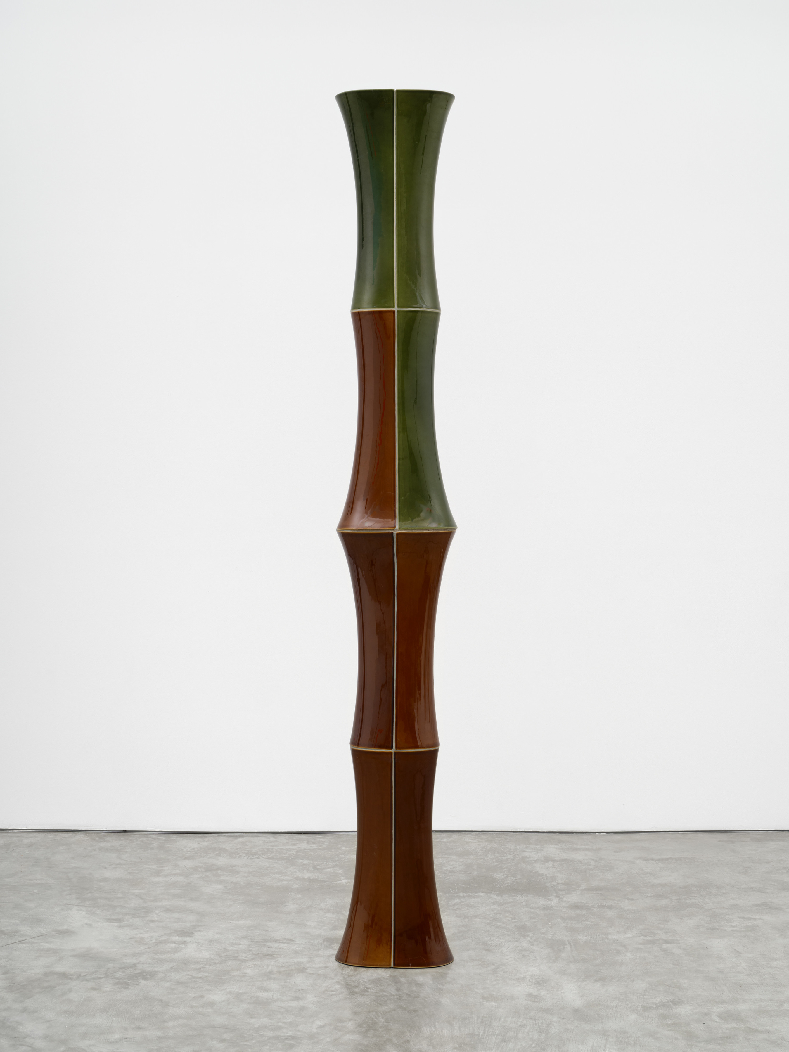 A freestanding ceramic sculpture with green and brown composite sloping parts. 