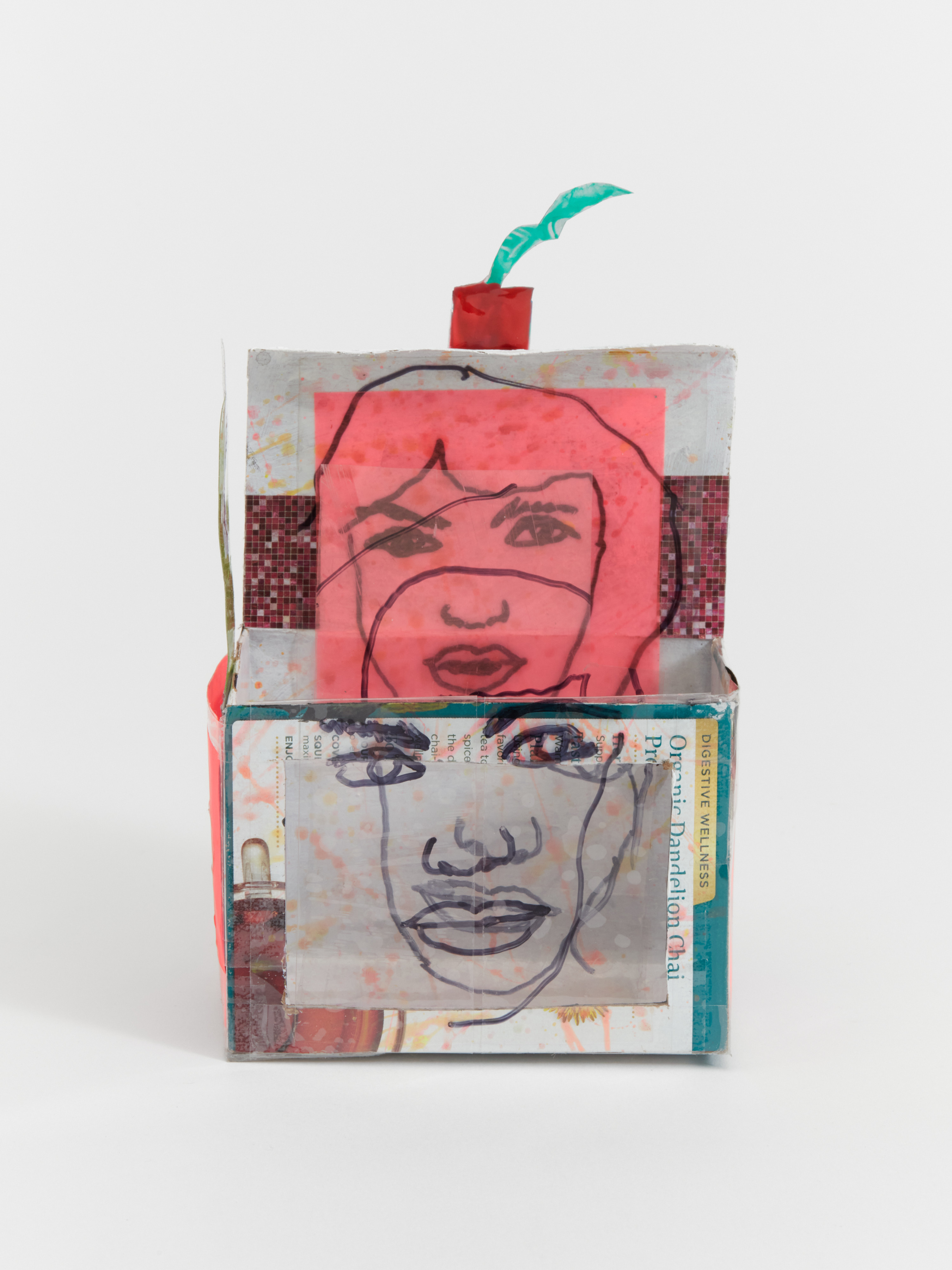 A box like sculpture with collaged surfaces and two line drawings of a woman's face. 