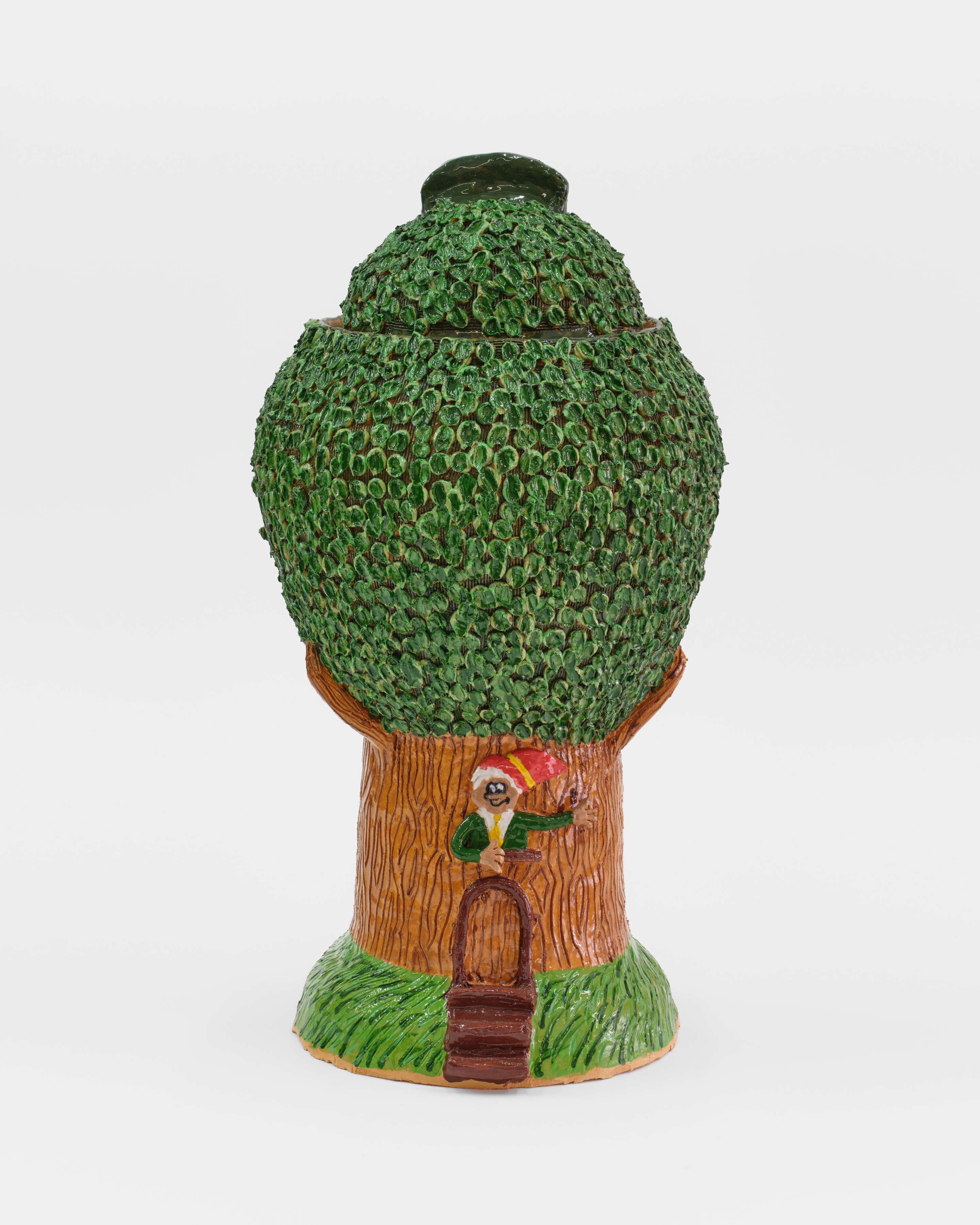 A ceramic sculpture of an elf welcoming the viewer to his house within a tree. 