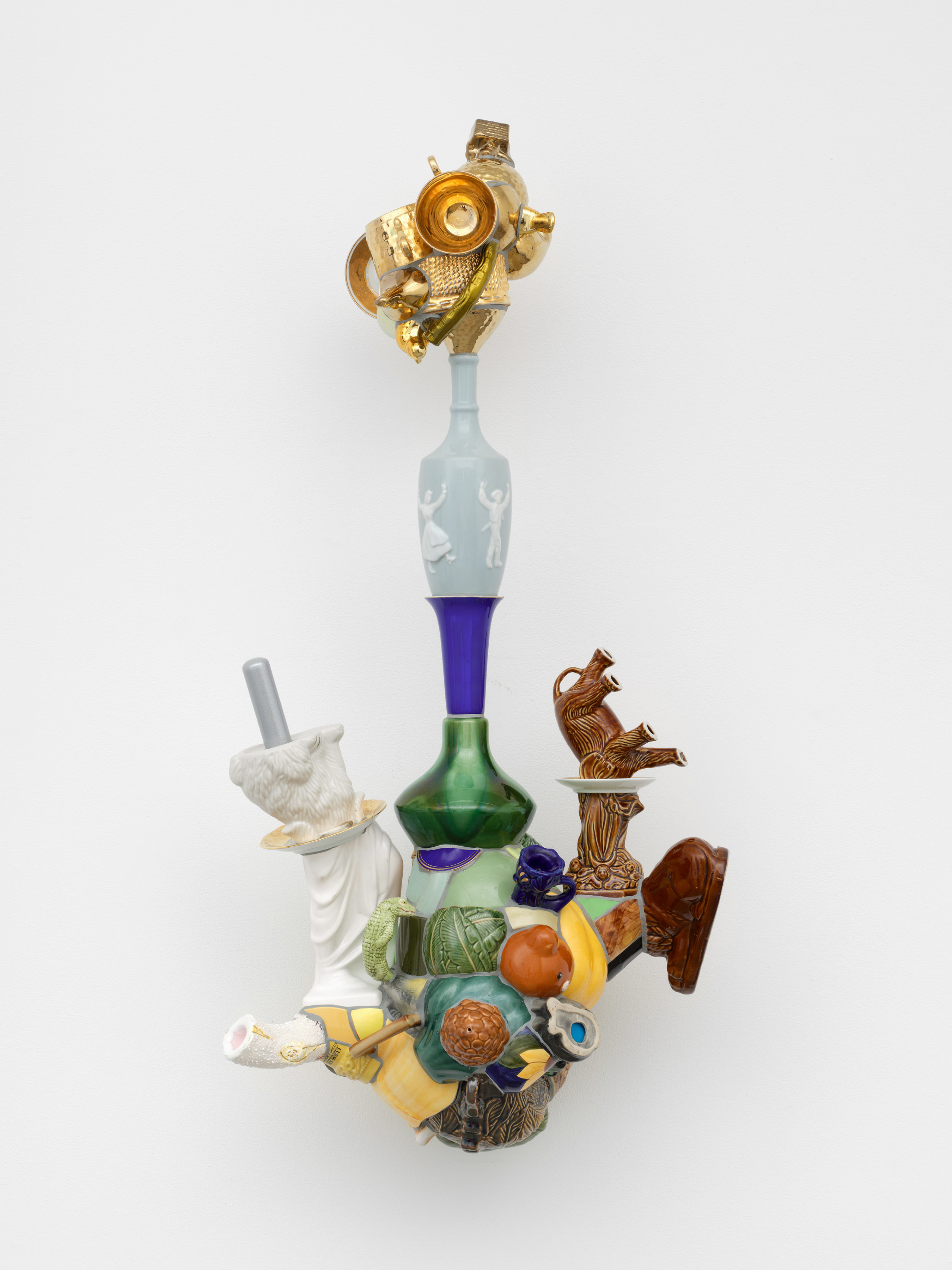 A composite ceramic sculpture with fragments of vases, cups and animal figurines mounted to the wall. 