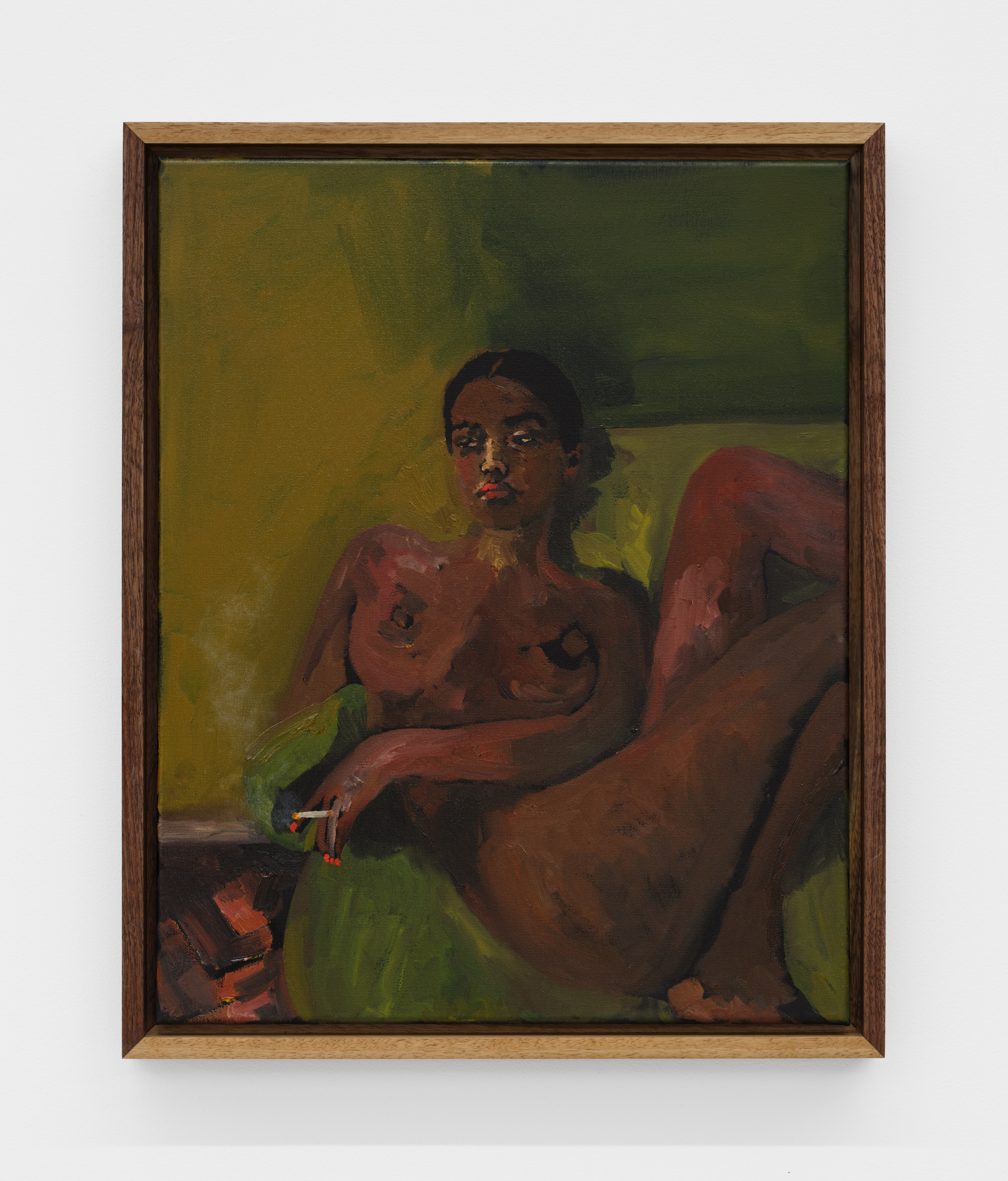 A woman rests nude on a green sofa while smoking a cigarette. 