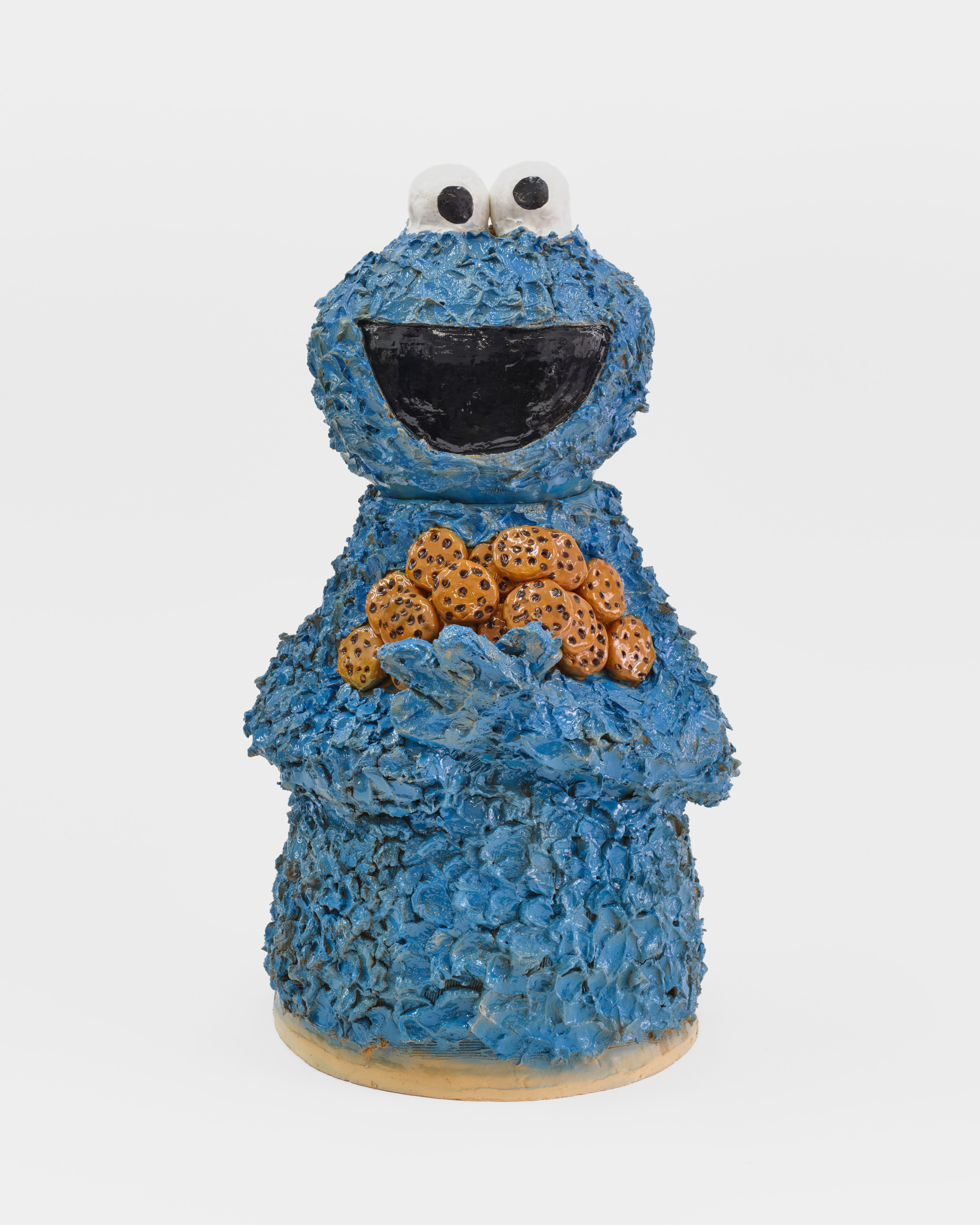 A ceramic sculpture of the Sesame Street Cookie Monster holding a bushel of chocolate chip cookies. 