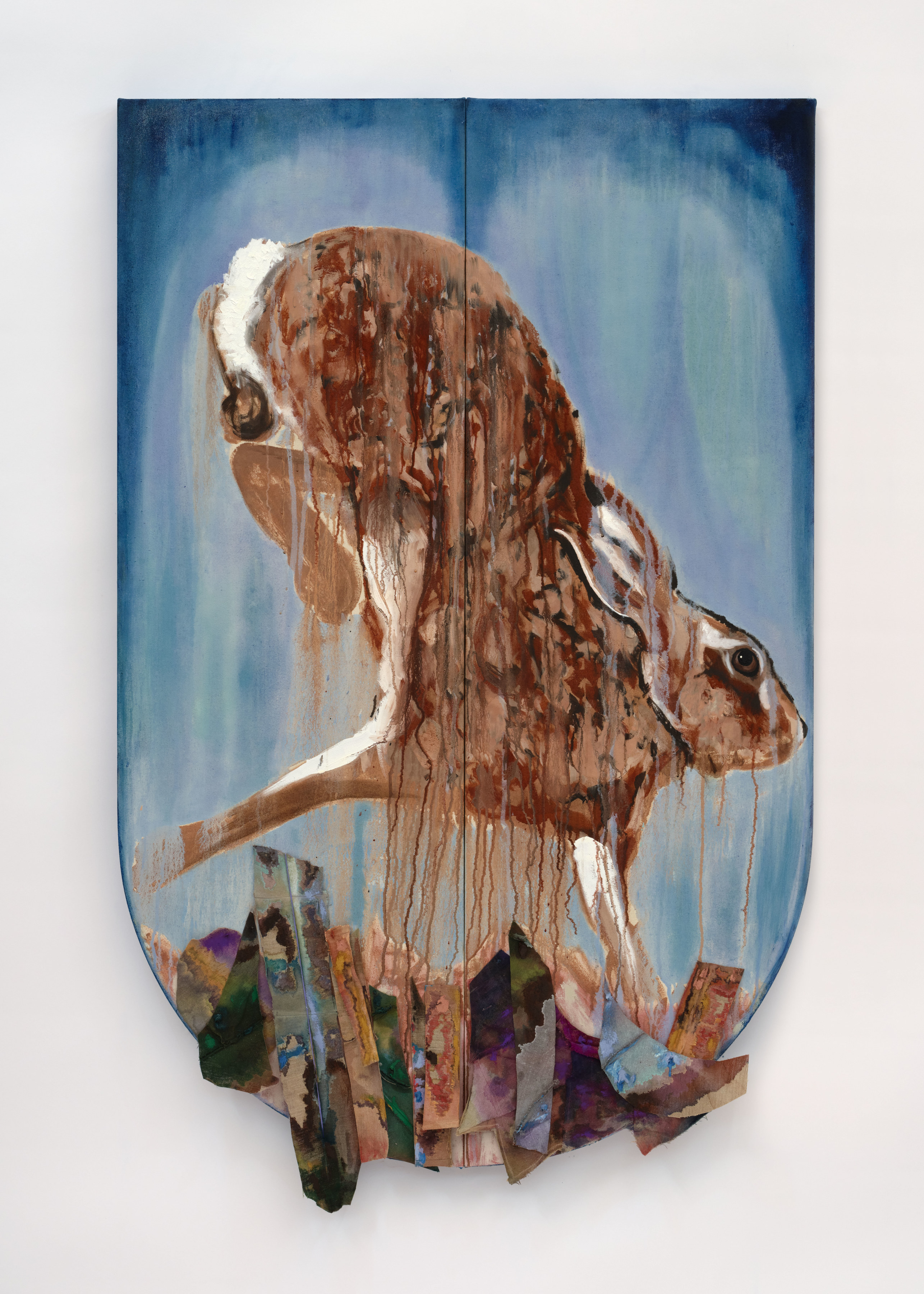 A crest shaped canvas with a painted portrayal of a running hare on a blue background with dyed pieces of fabric adhered and hanging from the bottom. 
