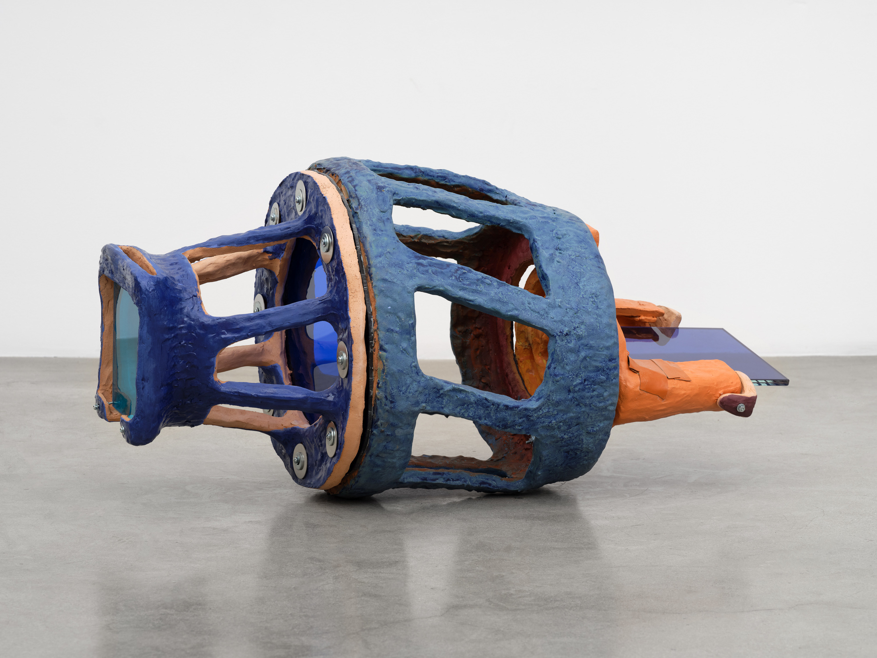 A ceramic sculpture with panes of glass on either end of a blue machine like form.