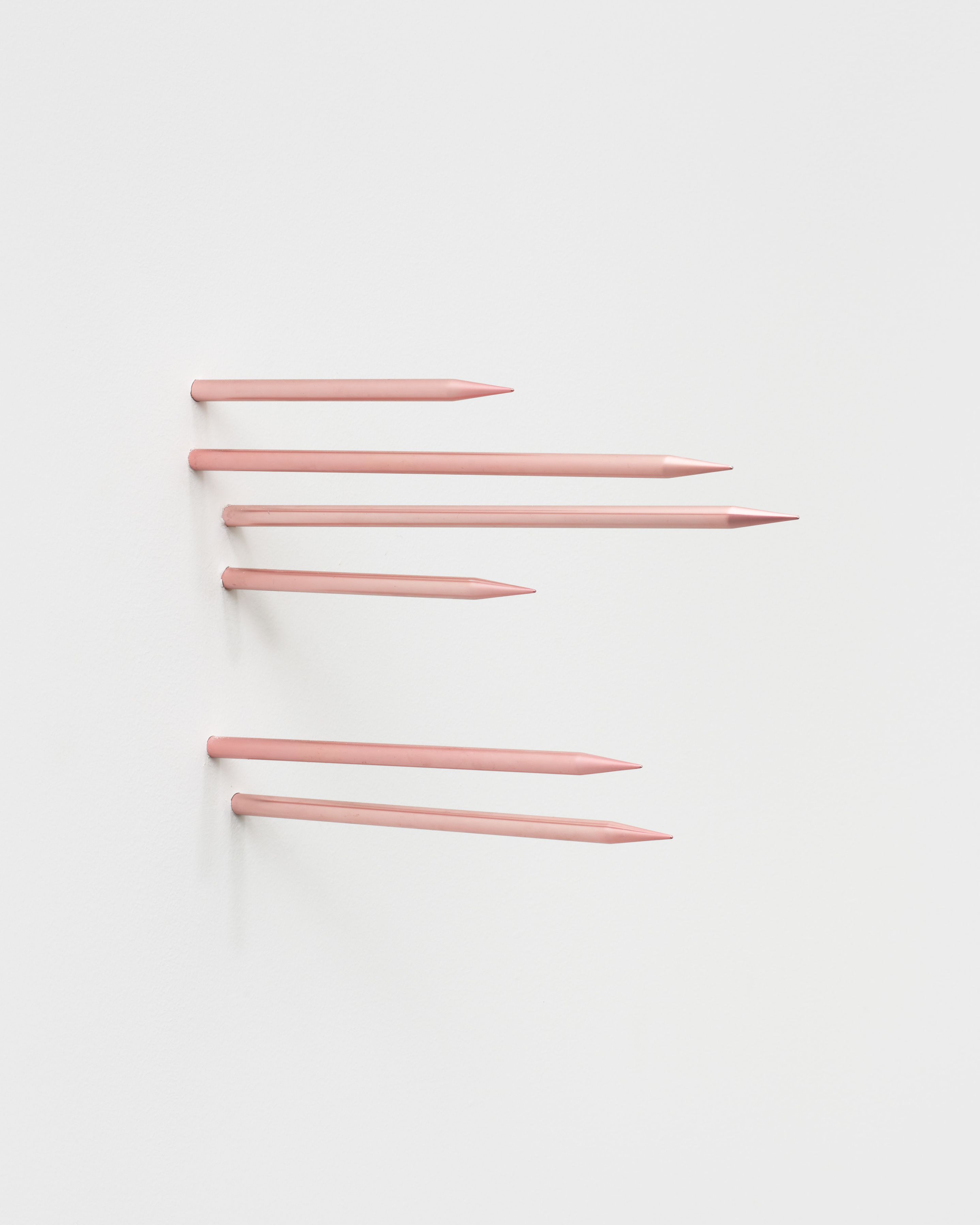 Six thin pink metal spikes emerge from the gallery wall. 