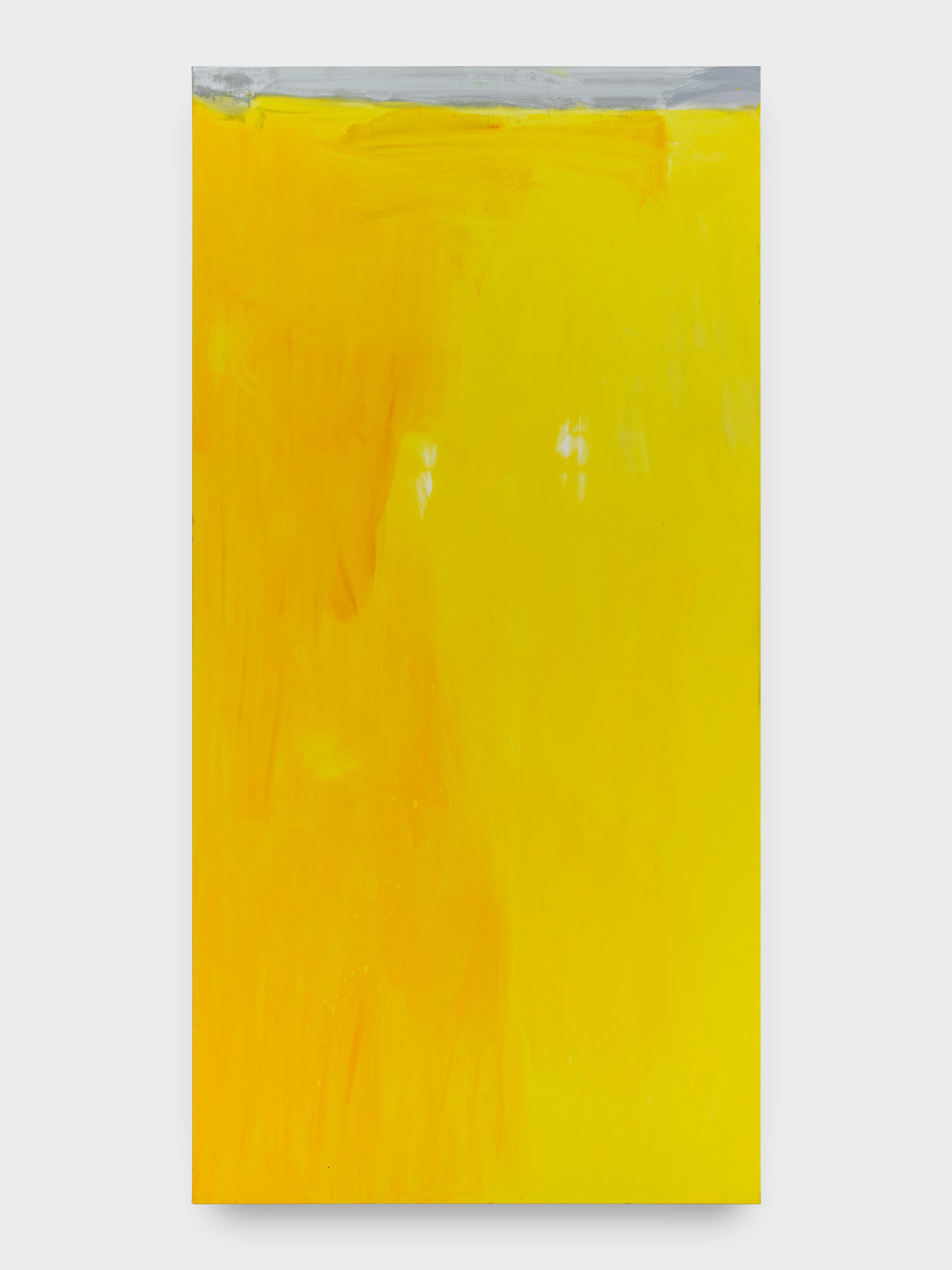 A large vertically rectangular painting in yellow hues with a swatch of silver pigment along the top of the canvas. 