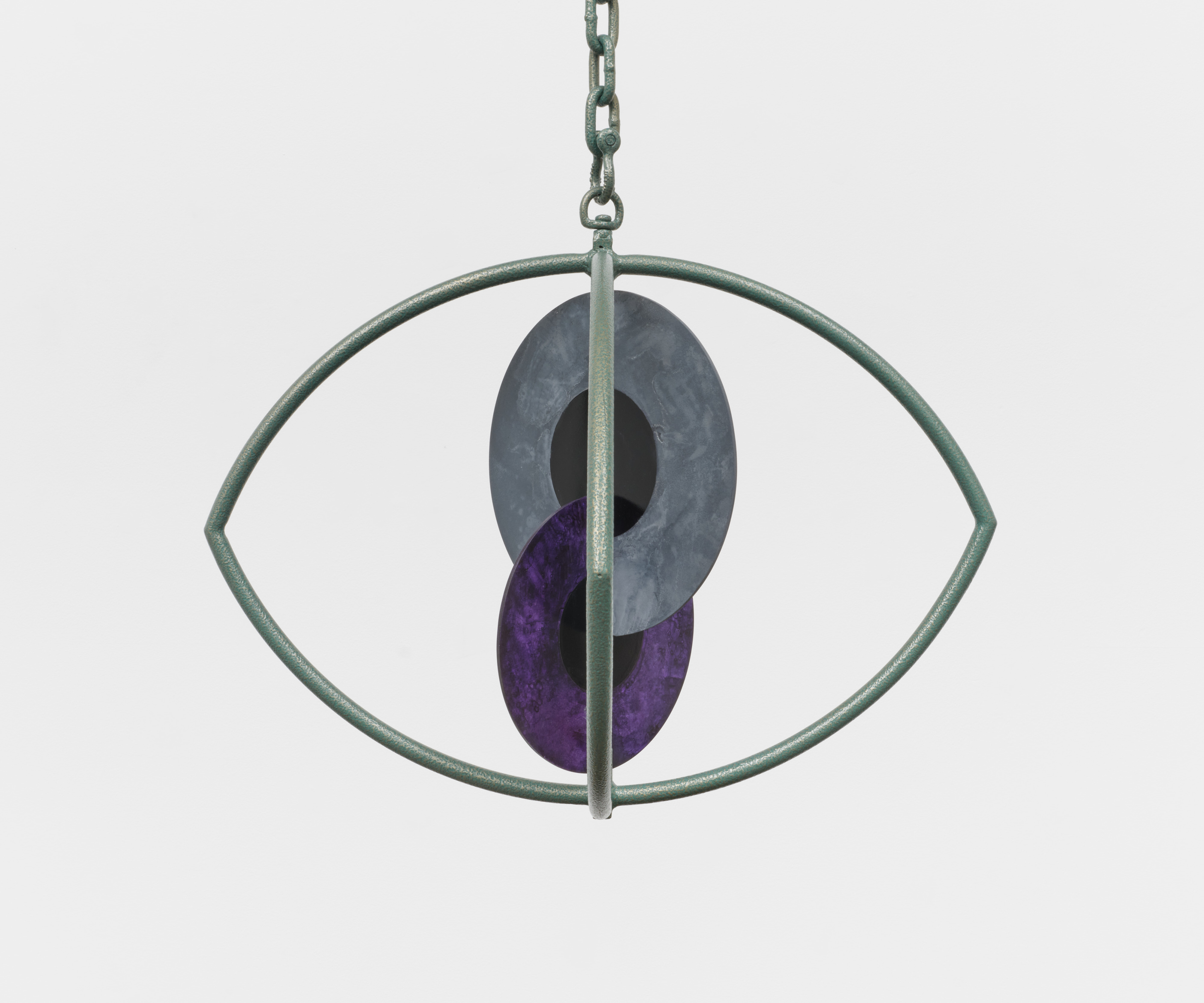 A sculpture with two interlocking metal iris' inside a metal eye hung from a chain in the ceiling.