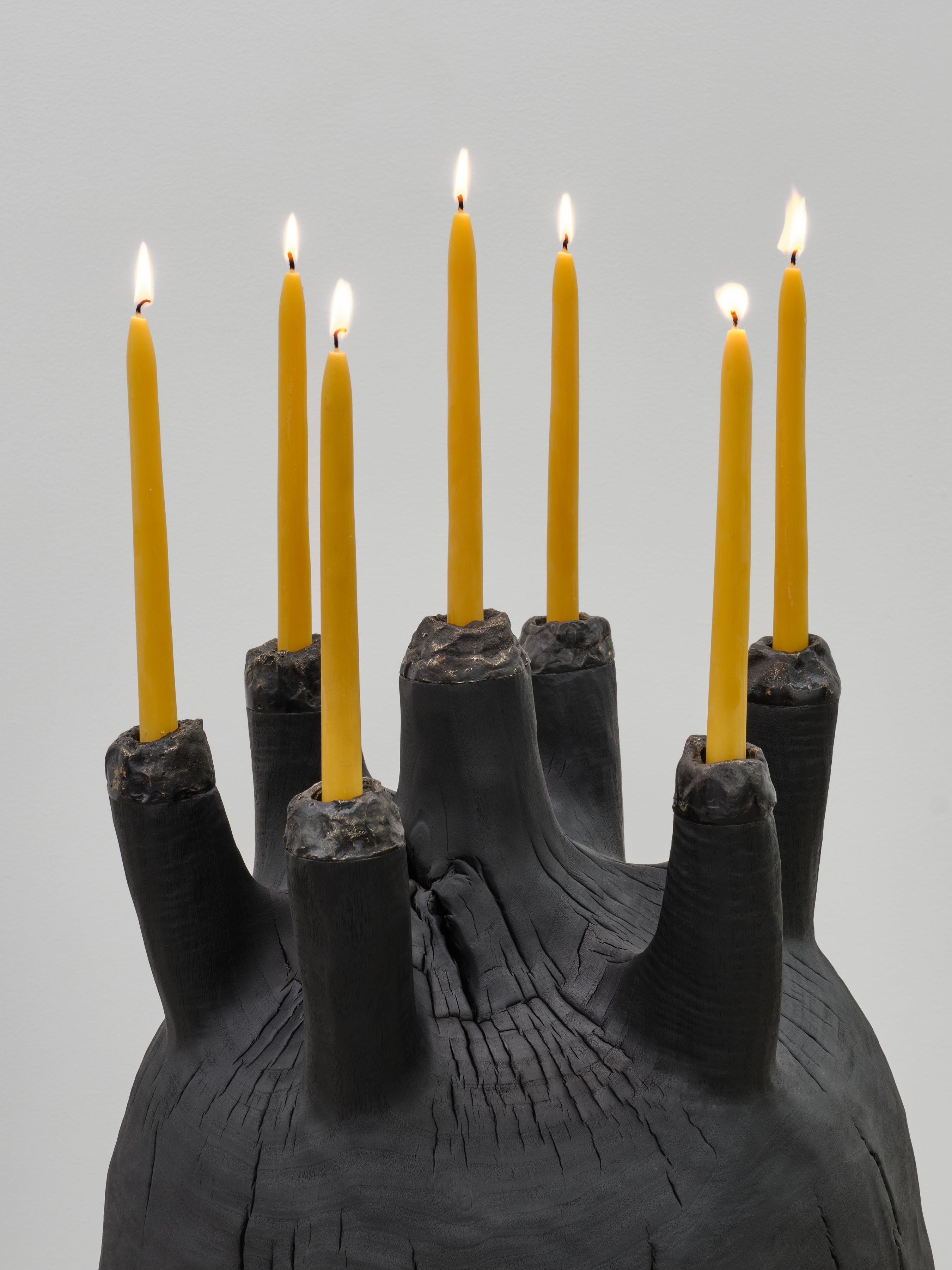 A detail of lit beeswax candles in "Seven Sisters"