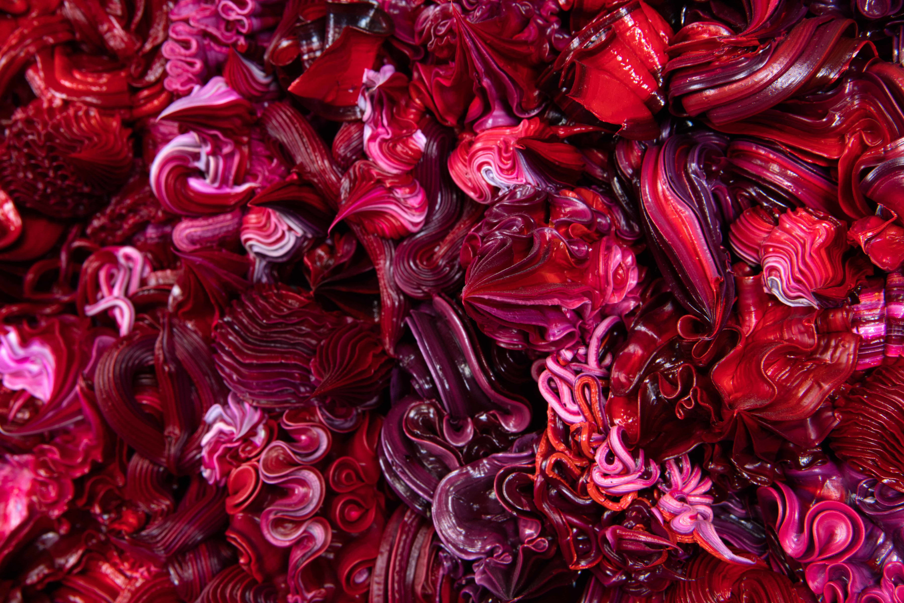 A zoomed in detail of dark red and purple whipped-cream-like dollops made of acrylic