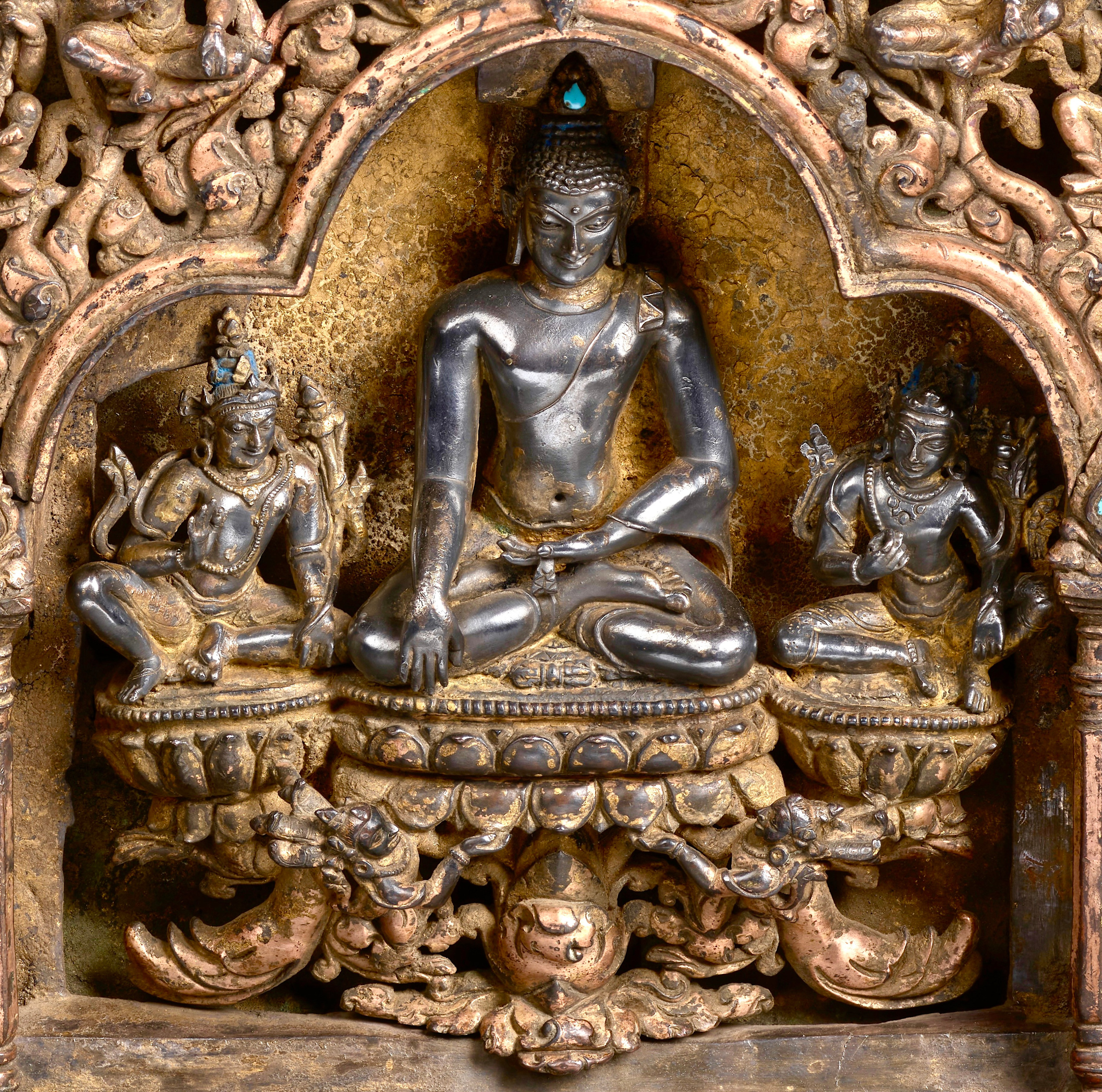 Detail of This plinth from an important eastern Indian stupa is assembled from four separately-cast gilt-copper arches (torana) with crouching elephants, rampant leogryphs, and jewel-topped pillars supporting trilobate spans, makara at either end of the crossbars, bodhisattvas and celestial figures above, and with kirtimukha at the apex.  