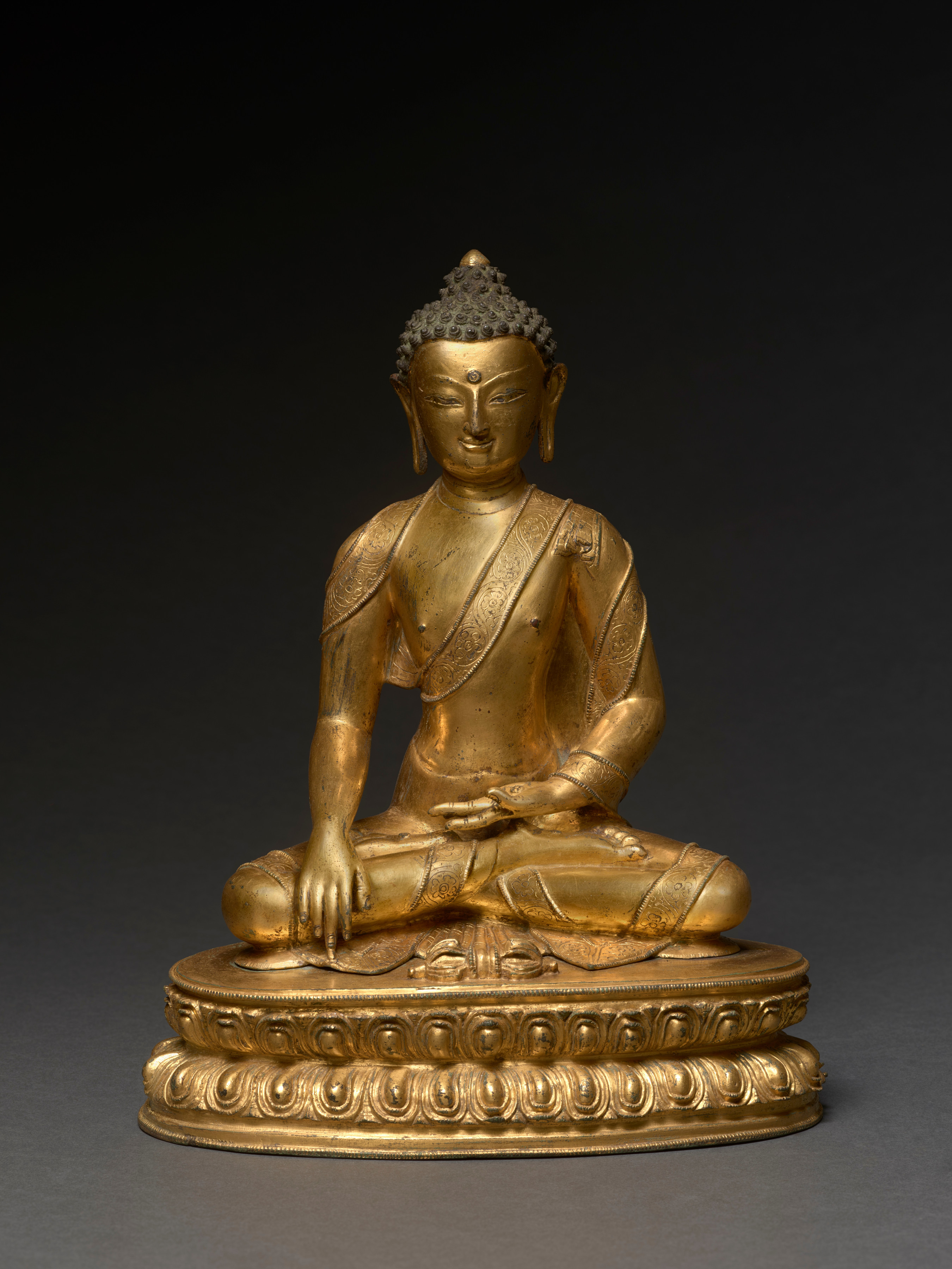 Buddha is seated on a double-lotus throne with a vajra-scepter sunk horizontally into the seat before him