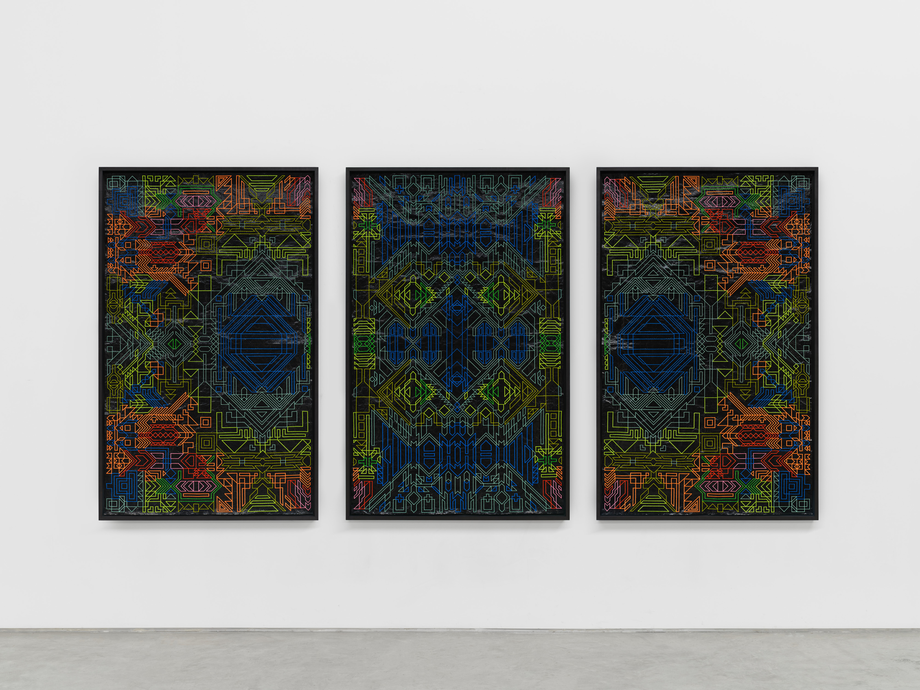 A triptych of framed artworks with neon orange, green and blue intricate embroidery on black roofing material.