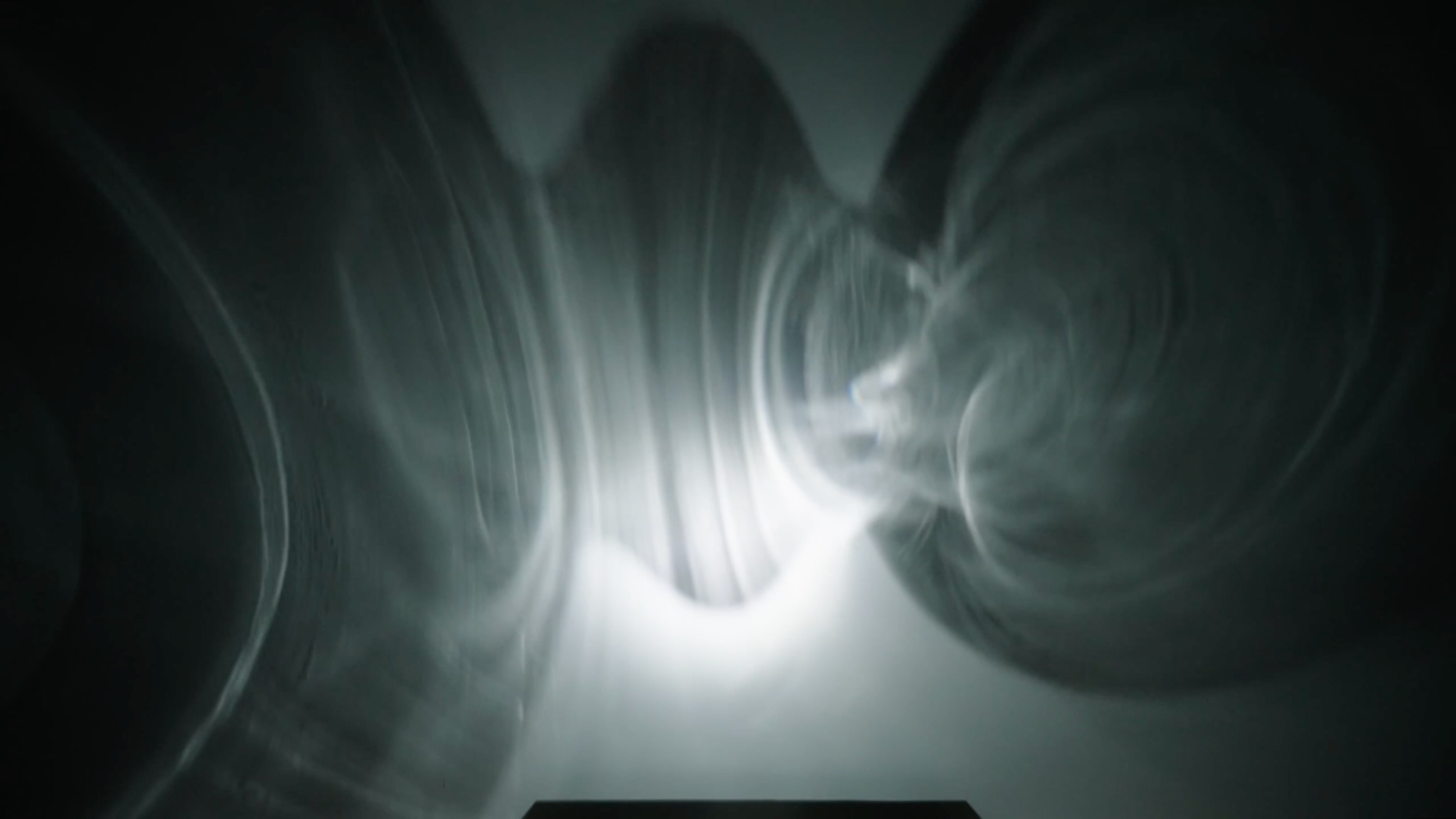 Still from Won Ju Lim's "Casting II" film with round refractions of light projected on a wall. 