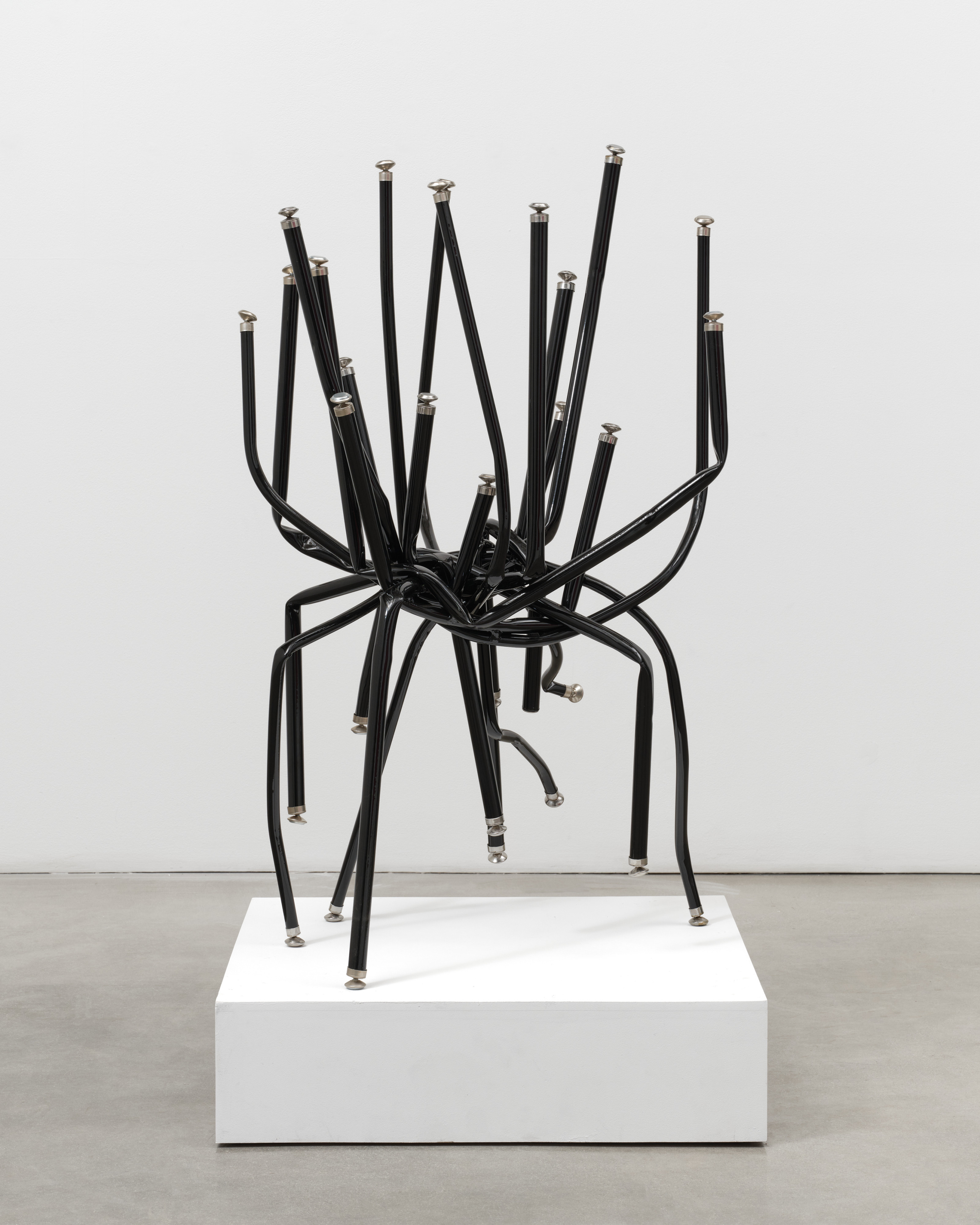 A free standing sculpture by Josh Callaghan of black metal chair legs entangled and extending skyward.