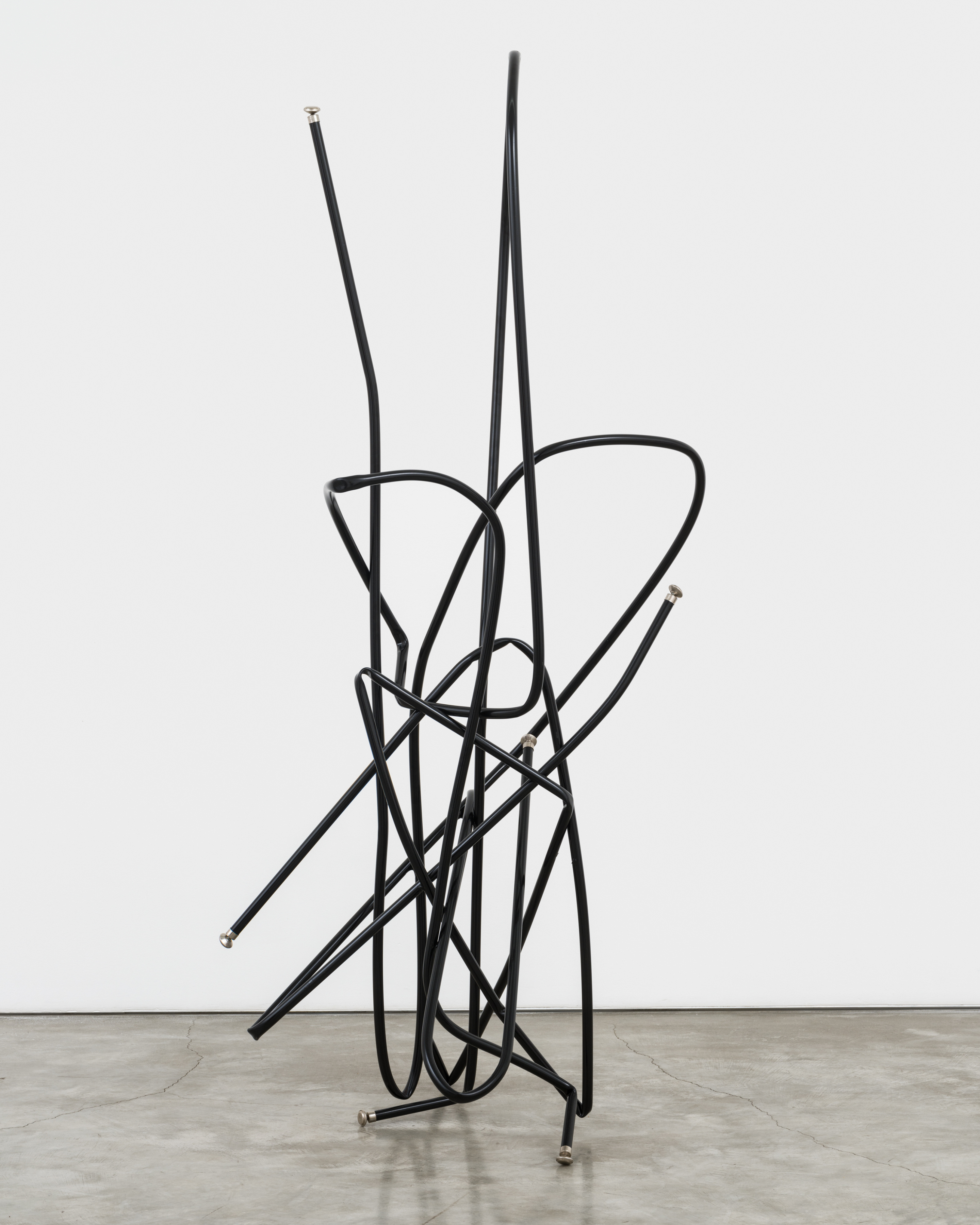 A freestanding sculpture by Josh Callaghan of black metal tubing arched and interlocking.