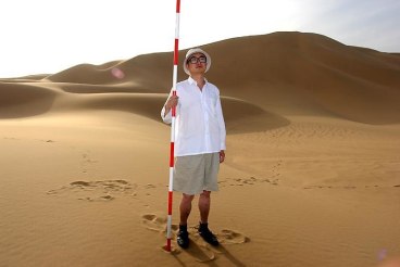 man holding a pole standing in a desert area