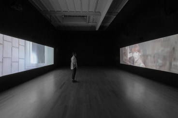 dark gallery with two video projections on opposite sides