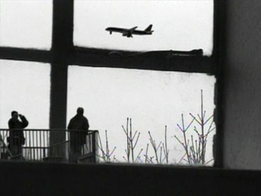 view of a window where two figures are spotted looking at a plane