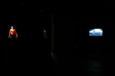 Installation view of several videos in a dark room