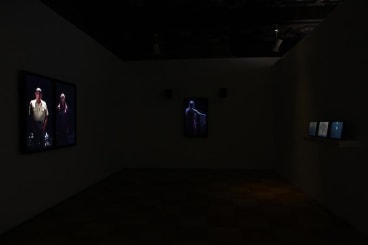 installation view of a dark room with several videos