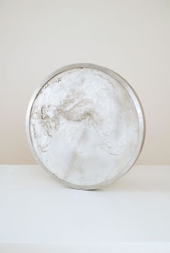 A large aluminum sculpture that resembles a coin