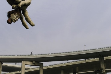 Image of a highway with a giant hand holding a severed head above it