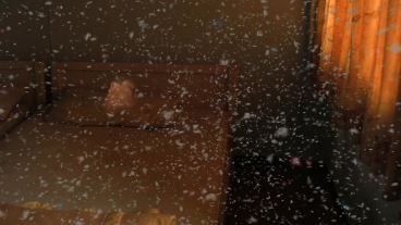still of a bed frame with feather-like particles in the air