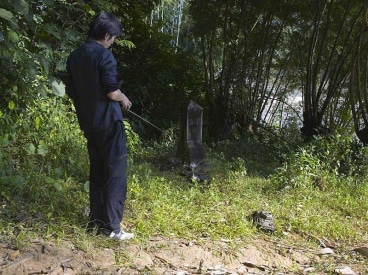 A man pointing a remote control with an extended antennae at a small machine