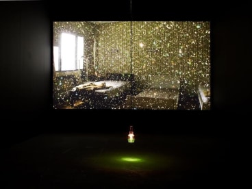 green lightbulb hanging in a dark room with a video screening