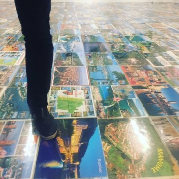 THE FOOT OF A MAN STANDING ON A FLOOR MADE OF KITSCH POSTCARDS FROM FRANCE&#039;S MOST ICONIC TOURISTIC SPOTS AT THE OPENING OF THE ART SHOW &quot;MICHEL HOUELLEBECQ: FRENCH BASHING&quot; ON FRIDAY IN NEW YORK