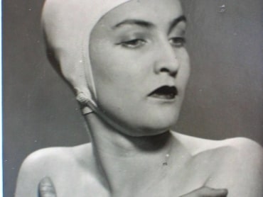 A woman wears a white swimming cap in a black and white photograph