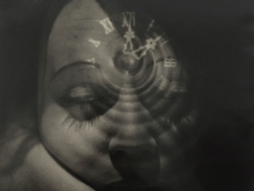 A vintage black and white double exposure photograph with a clock superimposing a woman's sleepy face.