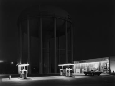 A gas station is photographed at night in black and white.
