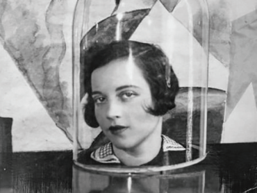 A woman's head is shown under a glass dome while the subject looks into the camera
