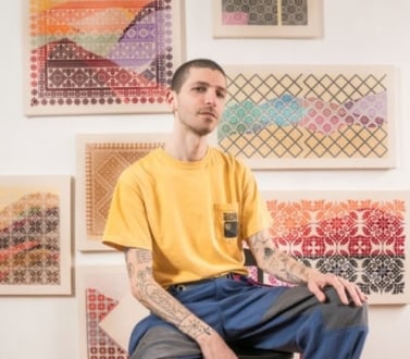 Jordan Nassar sitting in front of his woven artworks