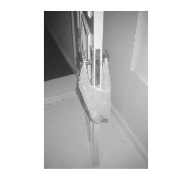 Black and white image of plastic bag attached to door handles