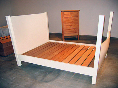 An installation view of a chest, dresser, and bed. 