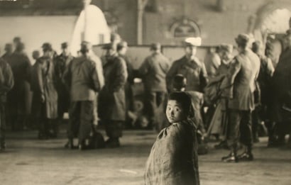 Werner Bischof - Pusan, South Korean (Little Beggar among American soldiers in station at Pusan, Korea), 1952 Gelatin silver exhibition print mounted to masonite&nbsp; | Bruce Silverstein Gallery