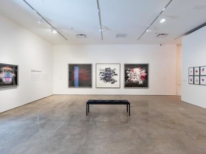 three red and black paintings of seating charts hung in gallery space